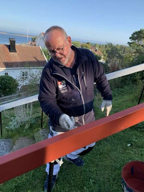 Per maler rødt rekkverk utendørs